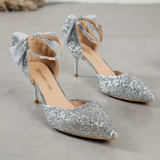 Elegant black glitter stiletto heel with pointed toe, ankle strap, and decorative bow for women